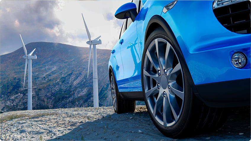Blue car close-up with wind turbines in the background