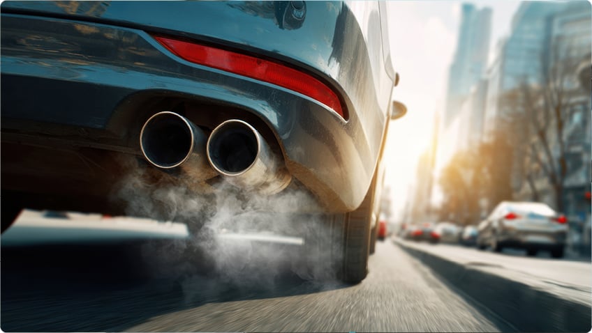 Car exhaust emitting smoke on city street, symbolizing vehicle emissions